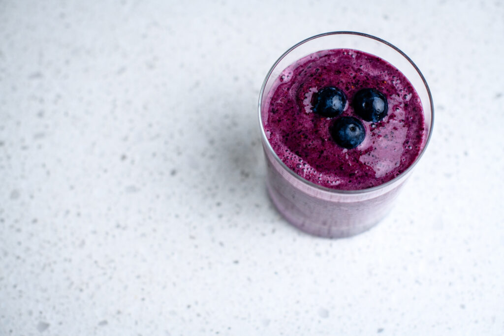 A glass of a purple blueberry smoothie