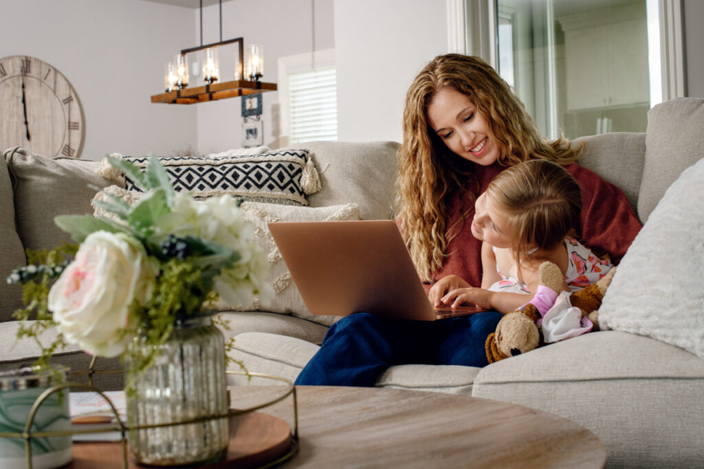 Mom and daughter together on couch on computer