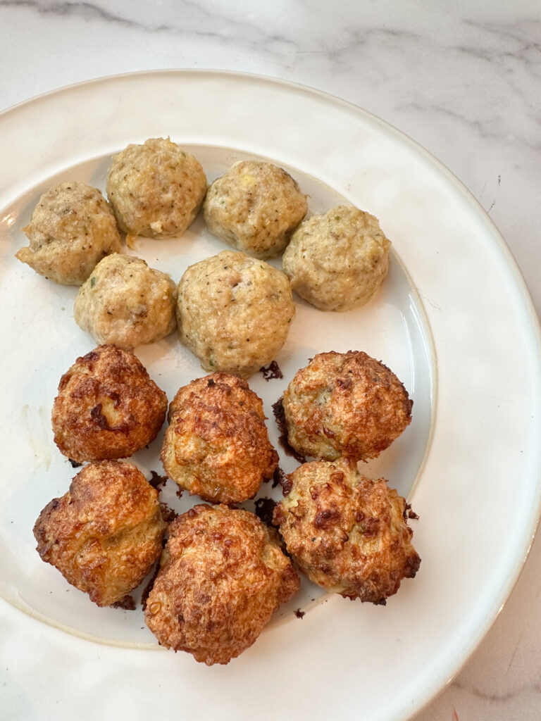 A white plate with 12 cooked meatballs. 6 of the meatballs are lighter colored because they were baked. The other 6 meatballs are darker in color because they were air-fried.