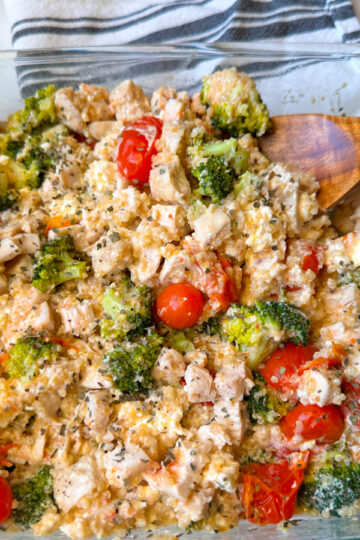 Chicken Quinoa & Feta Bake in a casserole dish with cubed chicken, broccoli, tomatoes, creamy feta, and basil sprinkled on top.
