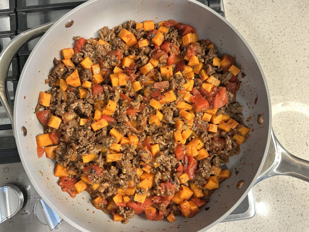 The same pan with cubed sweet potatoes, tomatoes, and the cooked ground beef added to it and mixed in.