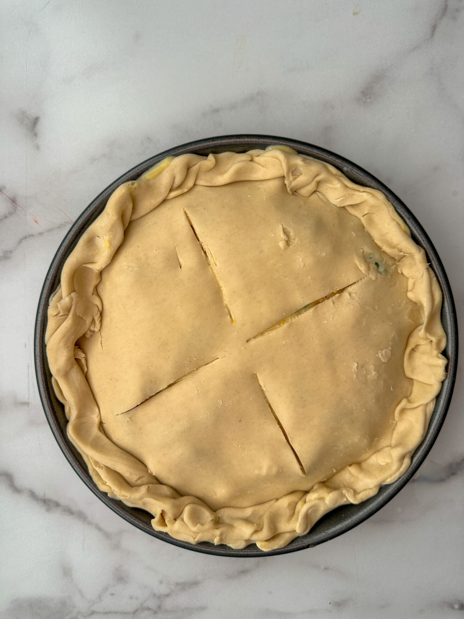 chicken pot pie in a round pan ready to be baked.