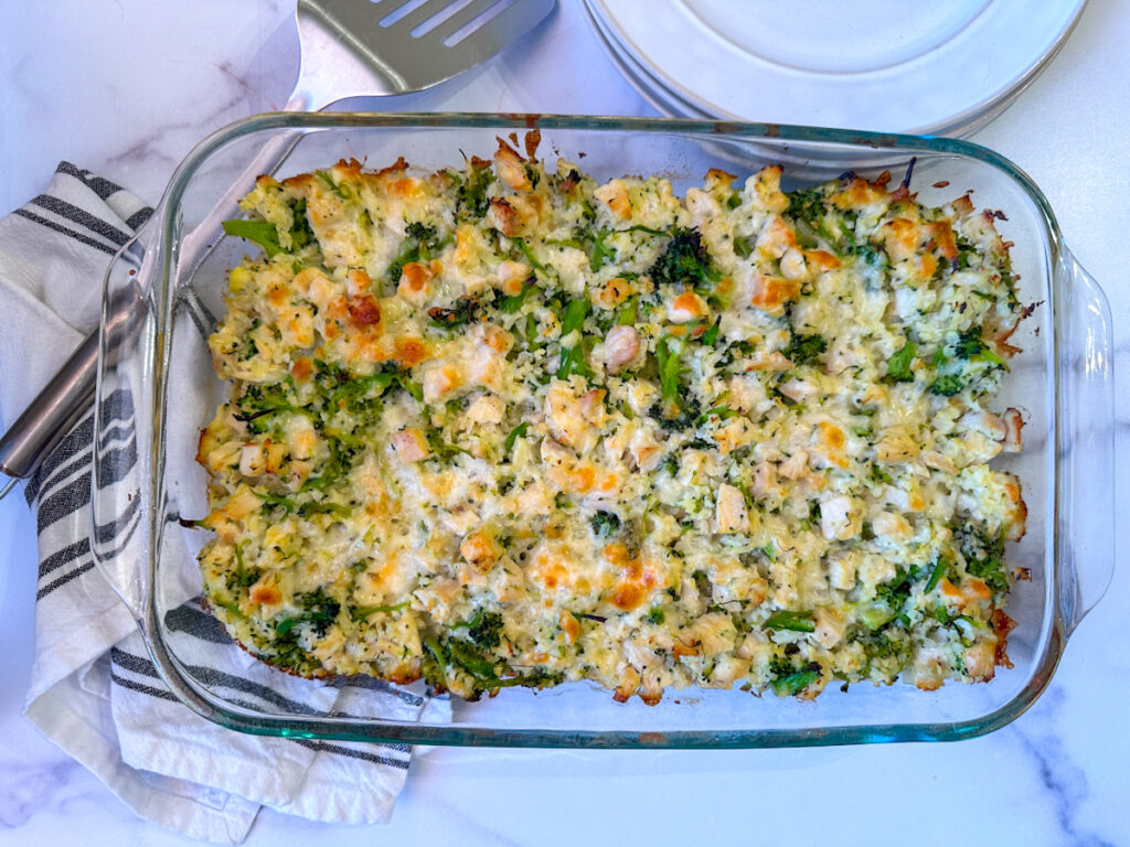 Casserole in a glass pyrex dish with chicken, broccoli, cauliflower, and cheese