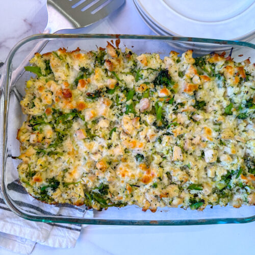 Casserole in a glass pyrex dish with chicken, broccoli, cauliflower, and cheese