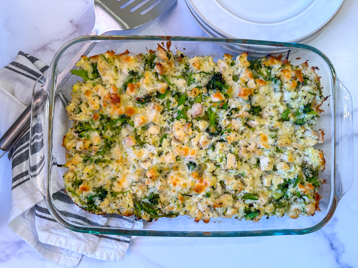 Casserole in a glass pyrex dish with chicken, broccoli, cauliflower, and cheese