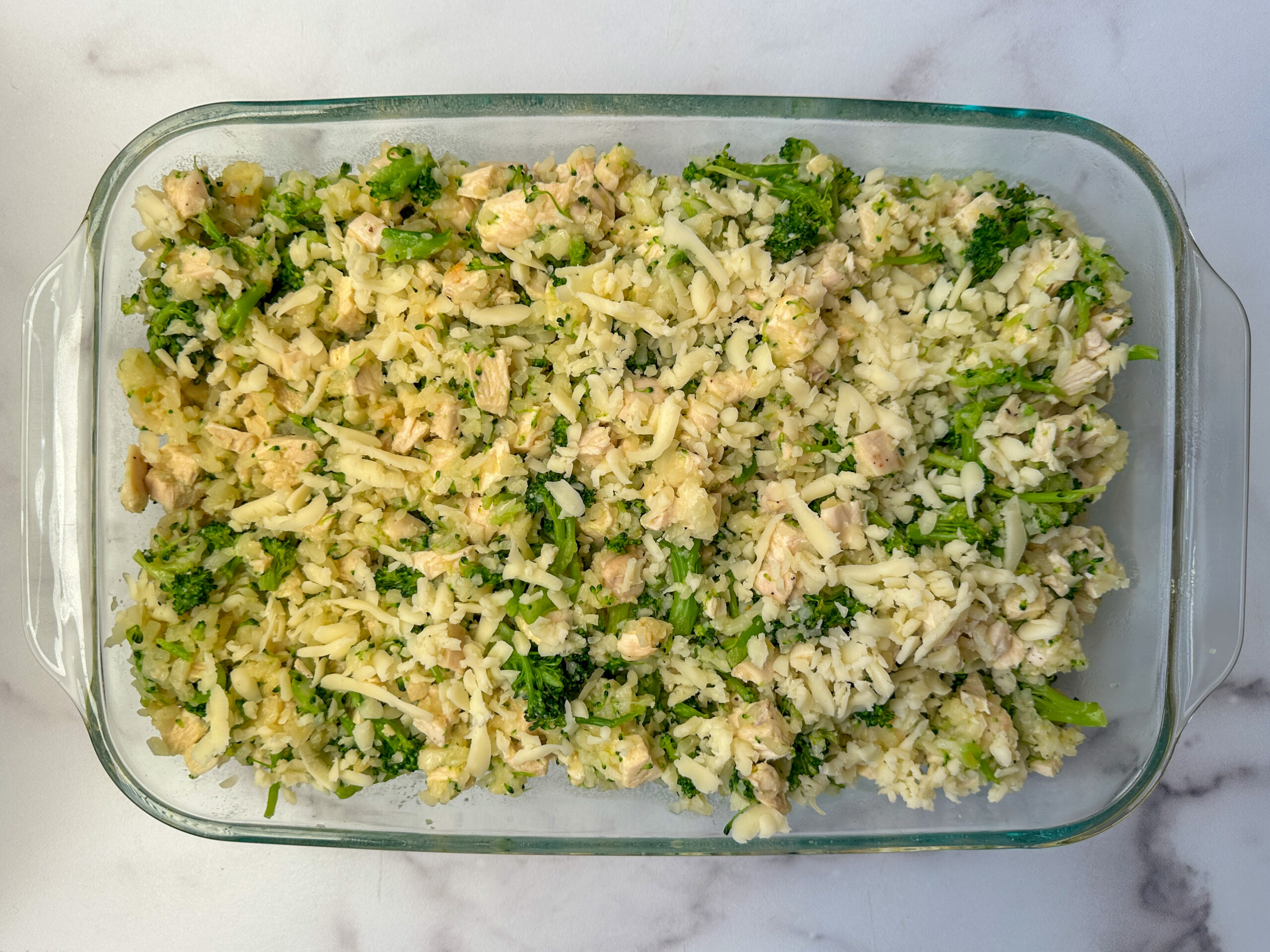 Broccoli Cauliflower Casserole ingredients mixed up in a large 9x13 glass baking dish.