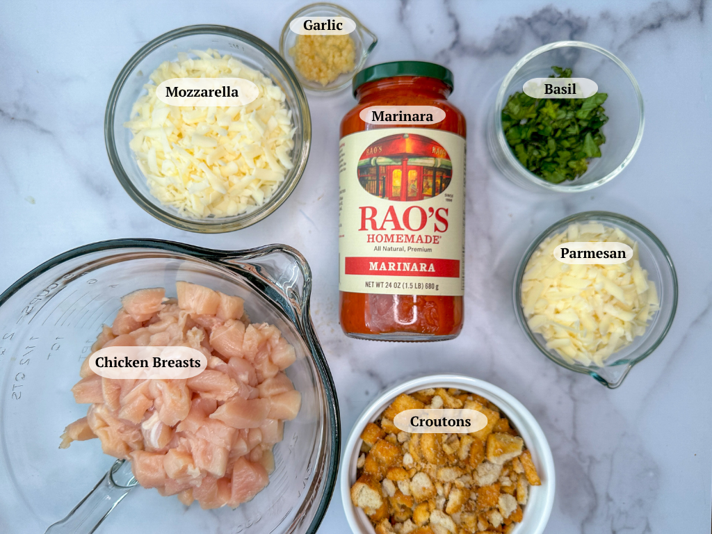 Chicken Parmesan Casserole ingredients: cubed chicken breast, shredded mozzarella, minced garlic, marinara, chopped basil, shredded parmesan, and crushed croutons.