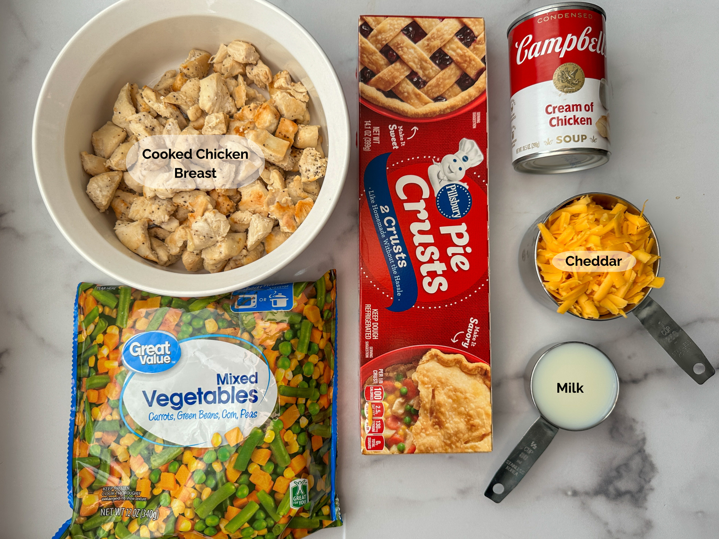 Chicken Pot Pie ingredients: cooked chopped chicken breast, pie crusts, cream of chicken soup, shredded cheddar, milk, and steamable mixed vegetables.