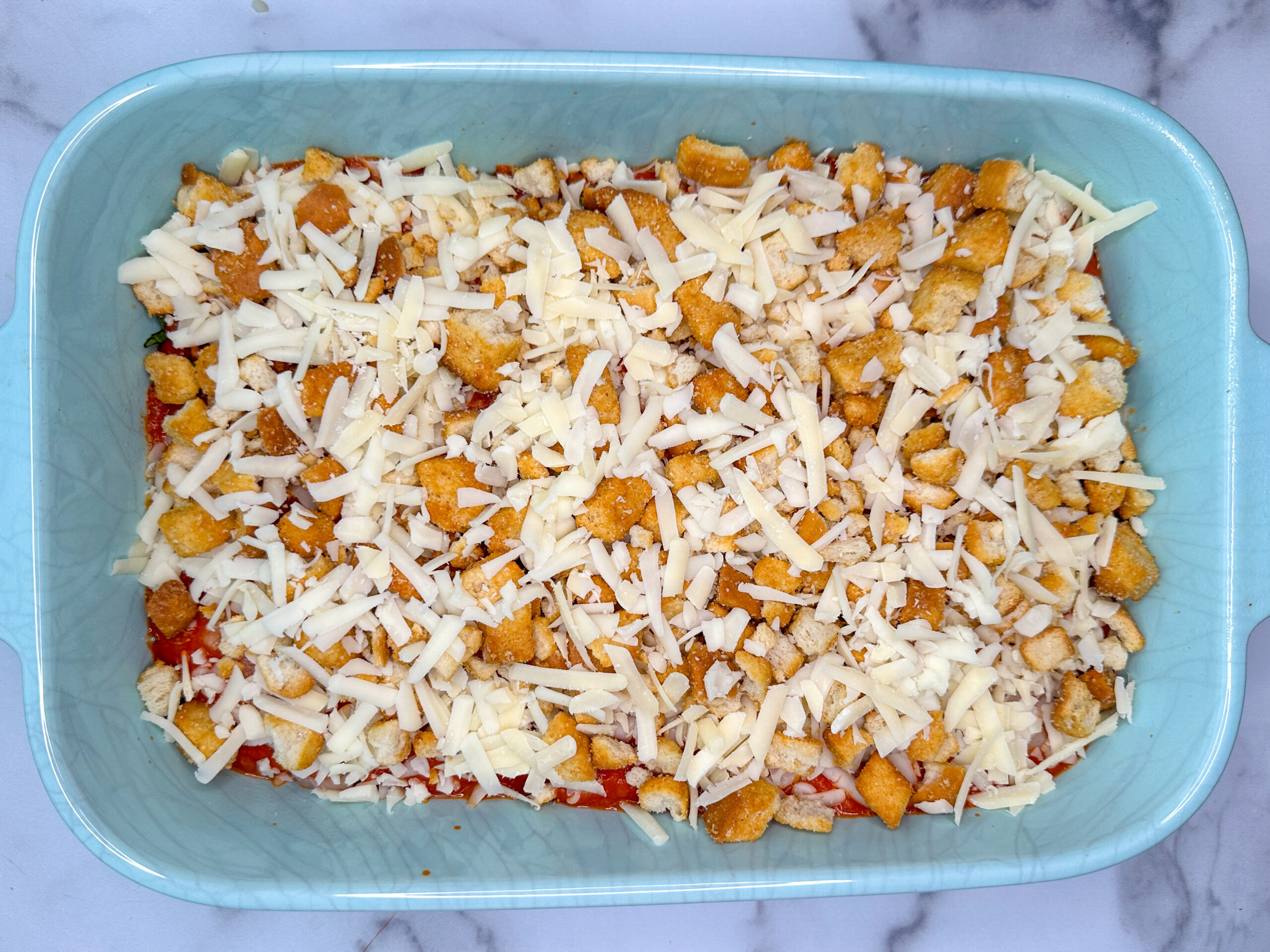 Chicken parmesan casserole with diced chicken breasts topped with garlic, basil, marinara, shredded mozzarella and parmesan cheese, and crushed croutons.