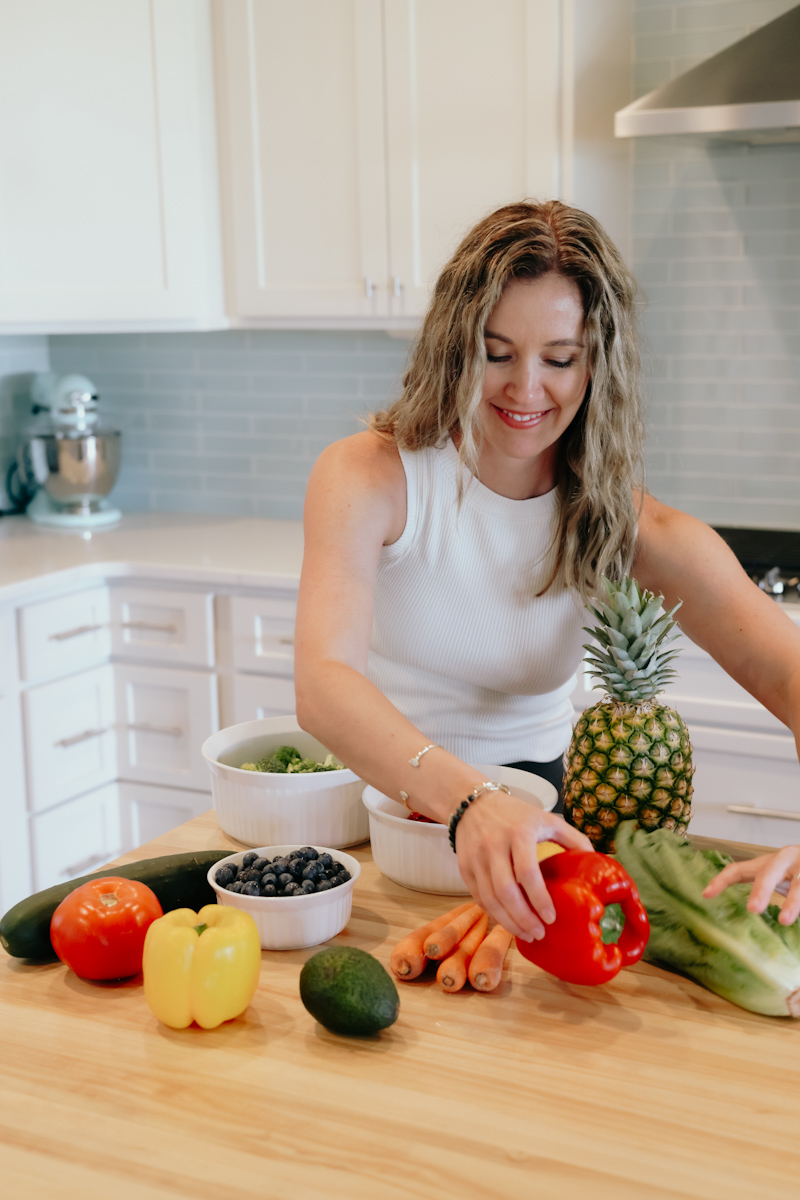 A woman placing fresh produce on her counter.