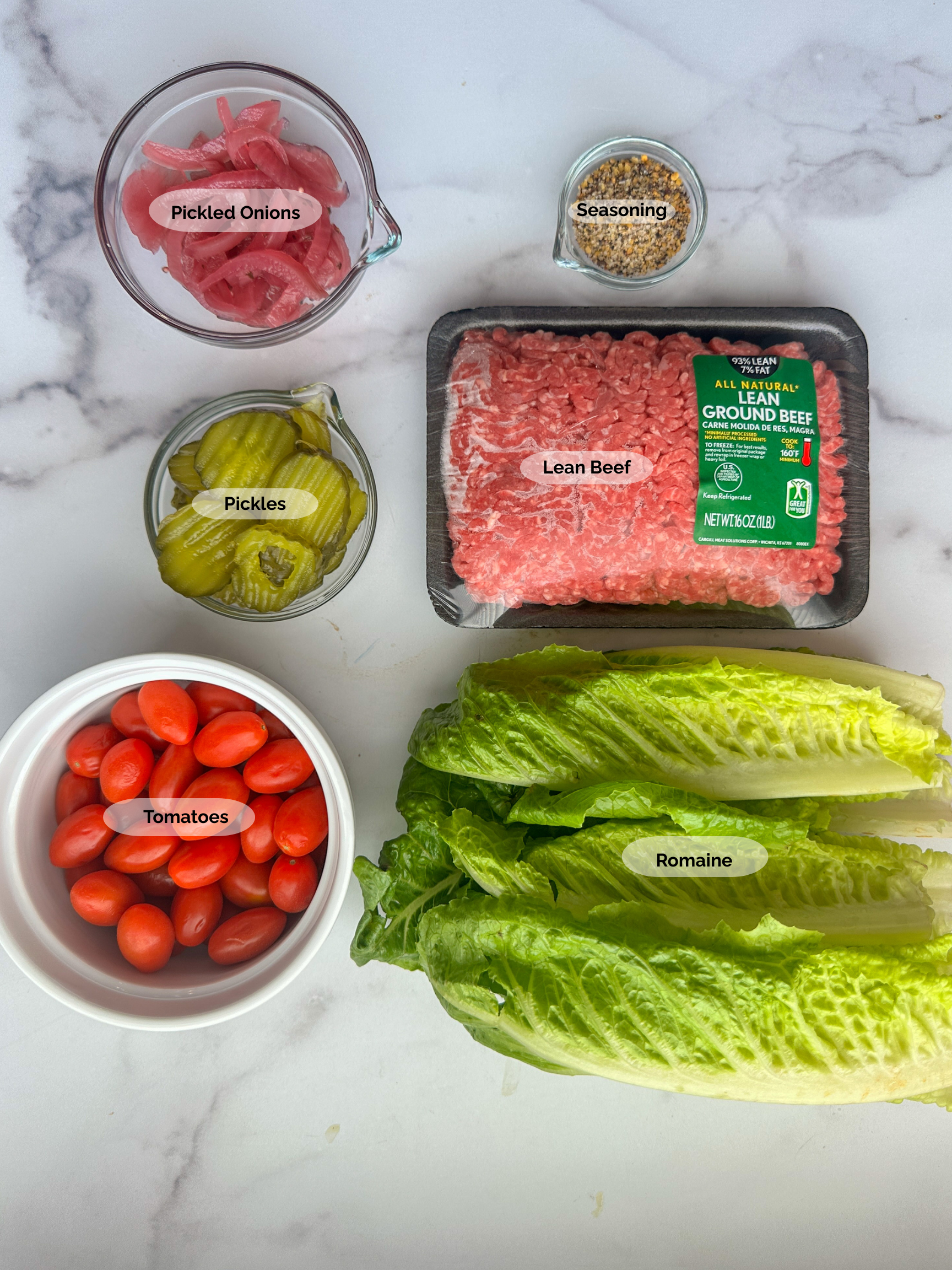 grilled slider bowl ingredients: lean ground beef, seasoning, pickled onions, pickles, tomatoes, and romaine lettuce.