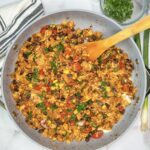 Skillet with cooked ground turkey, black beans, corn, fire roasted tomatoes, melted cheese, and topped with sliced green onions.