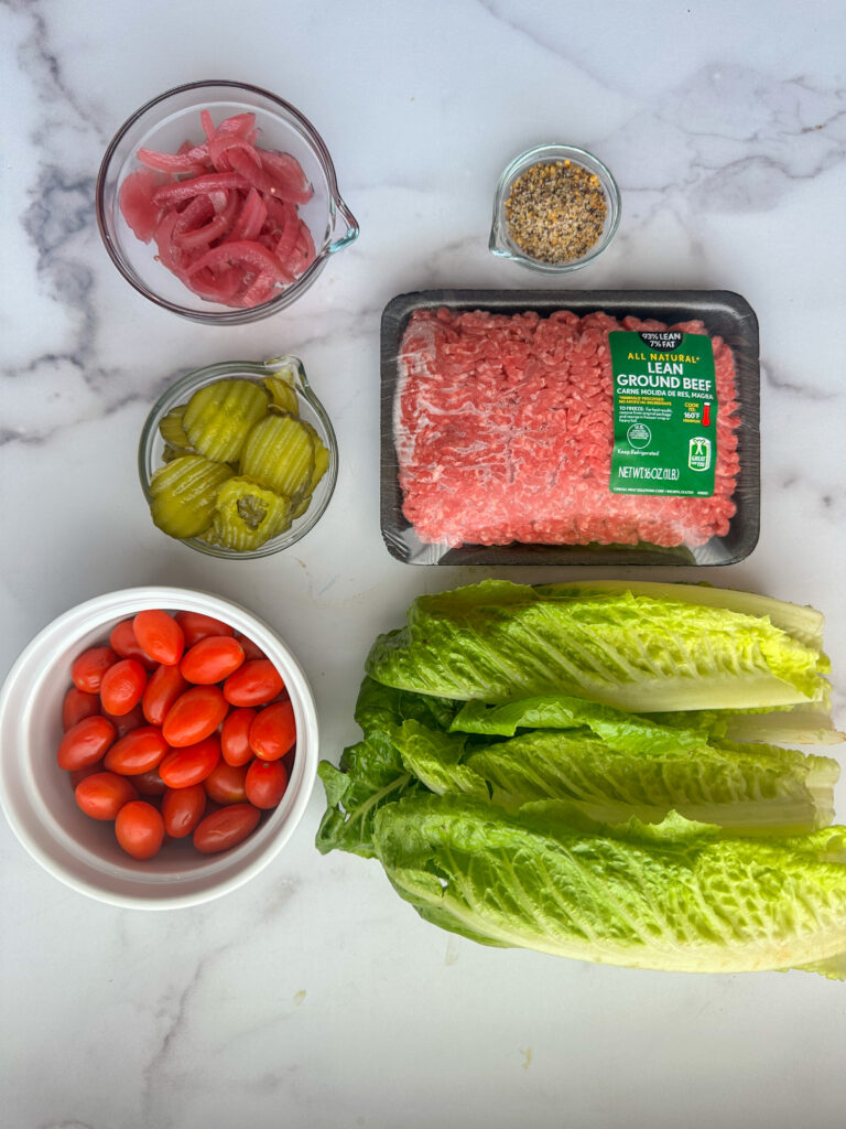 Grilled slider bowl ingredients: lean ground beef, tomatoes, romaine, pickles, pickled red onions, and seasoning.