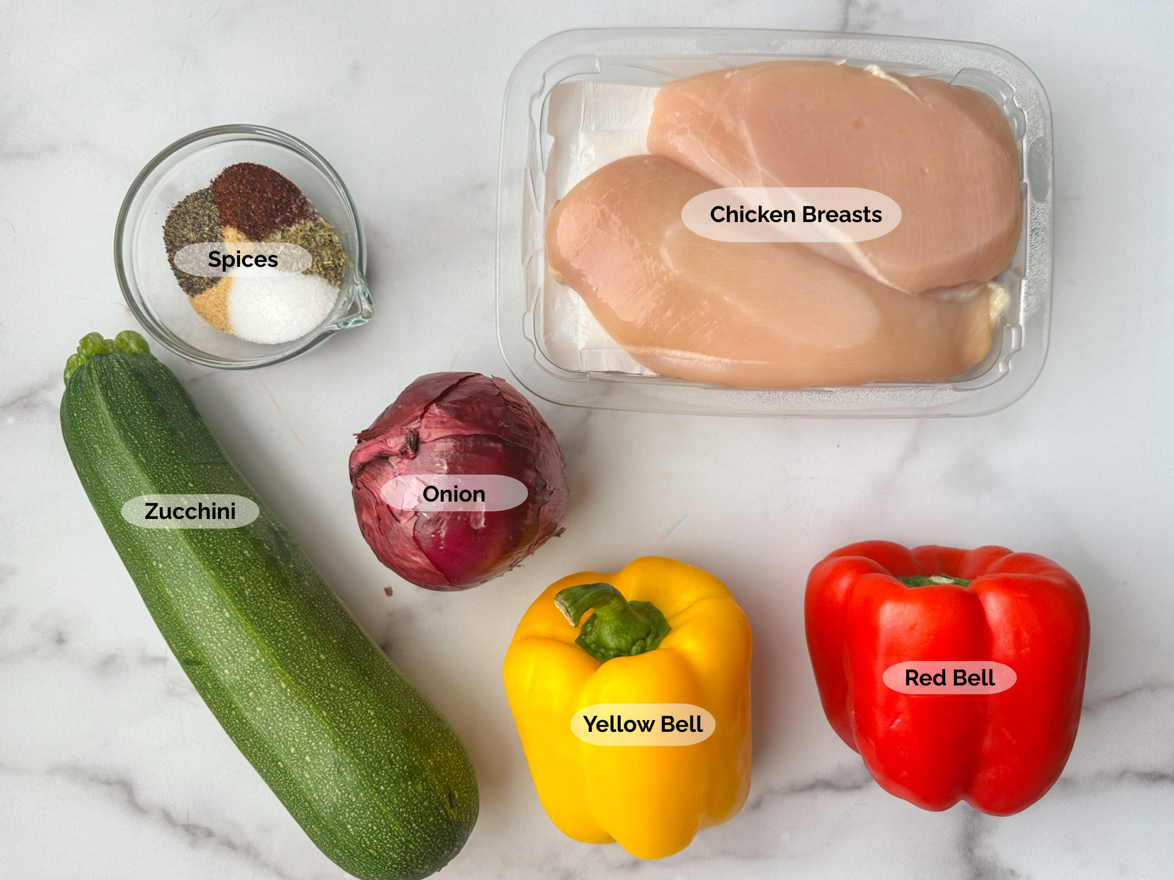 Air Fryer Chicken & Veggies ingredients: chicken breasts, spices, zucchini, onion, red bell pepper, and yellow bell pepper.