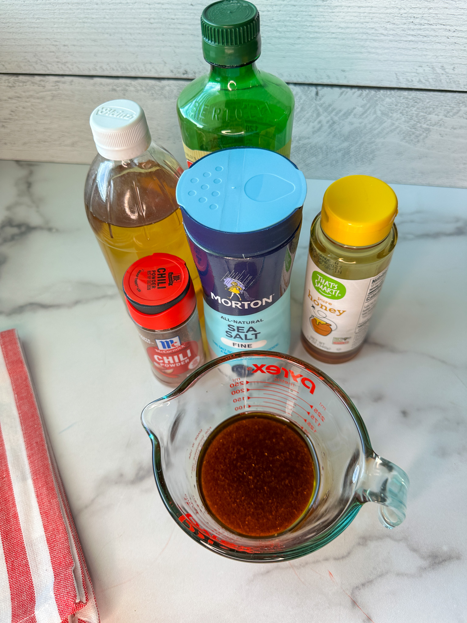 healthy cowboy caviar salad dressing ingredients mixed into a mixing cup: olive oil, apple cider vinegar, salt, and honey.