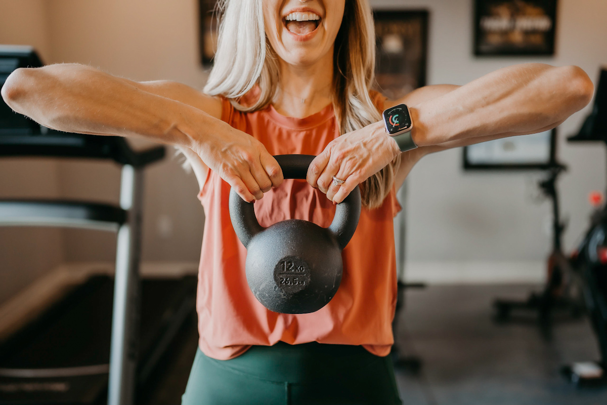 A woman lifting a kettle bell into an upright row.