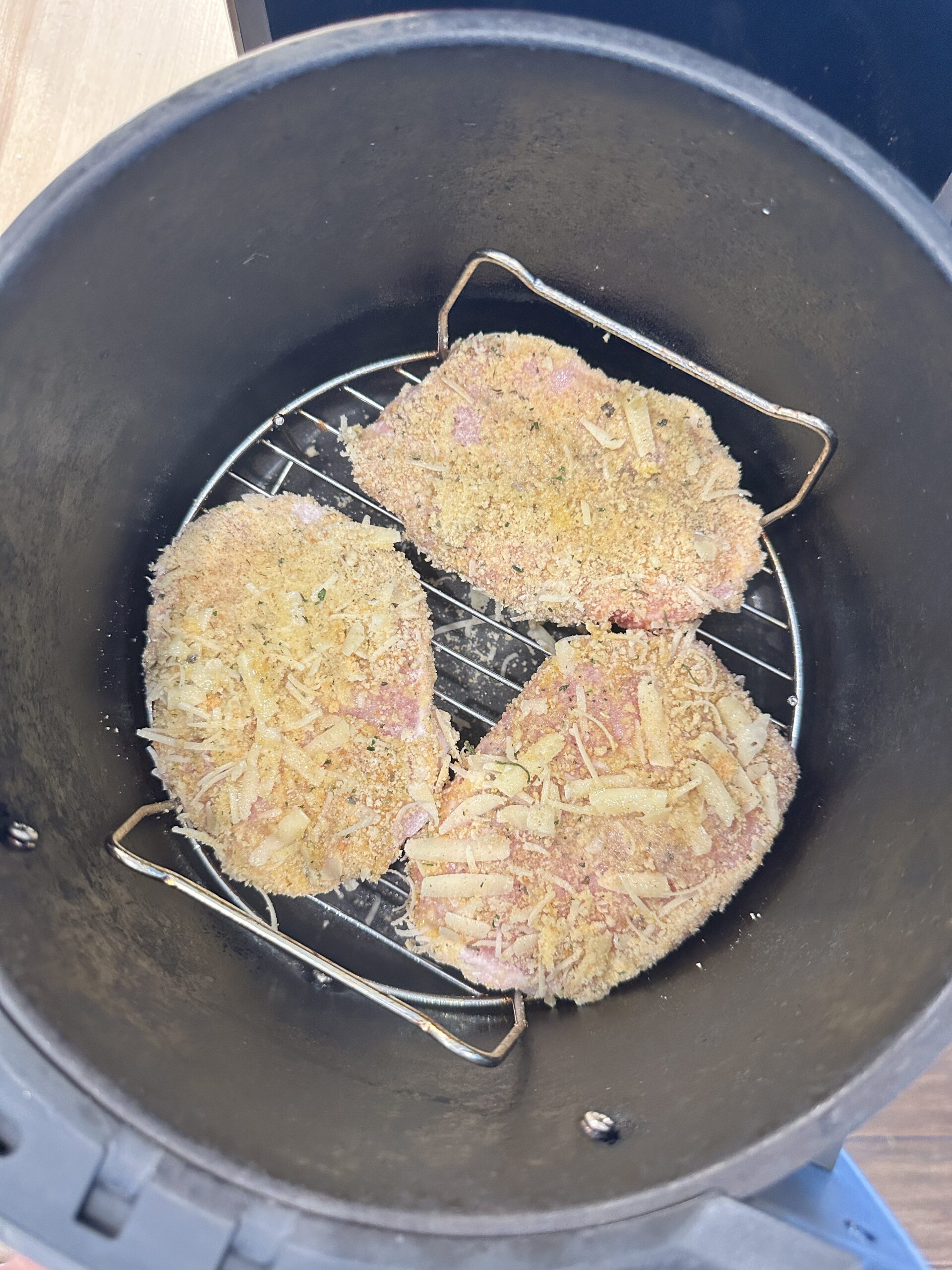 3 breaded pork chops in an air fryer.