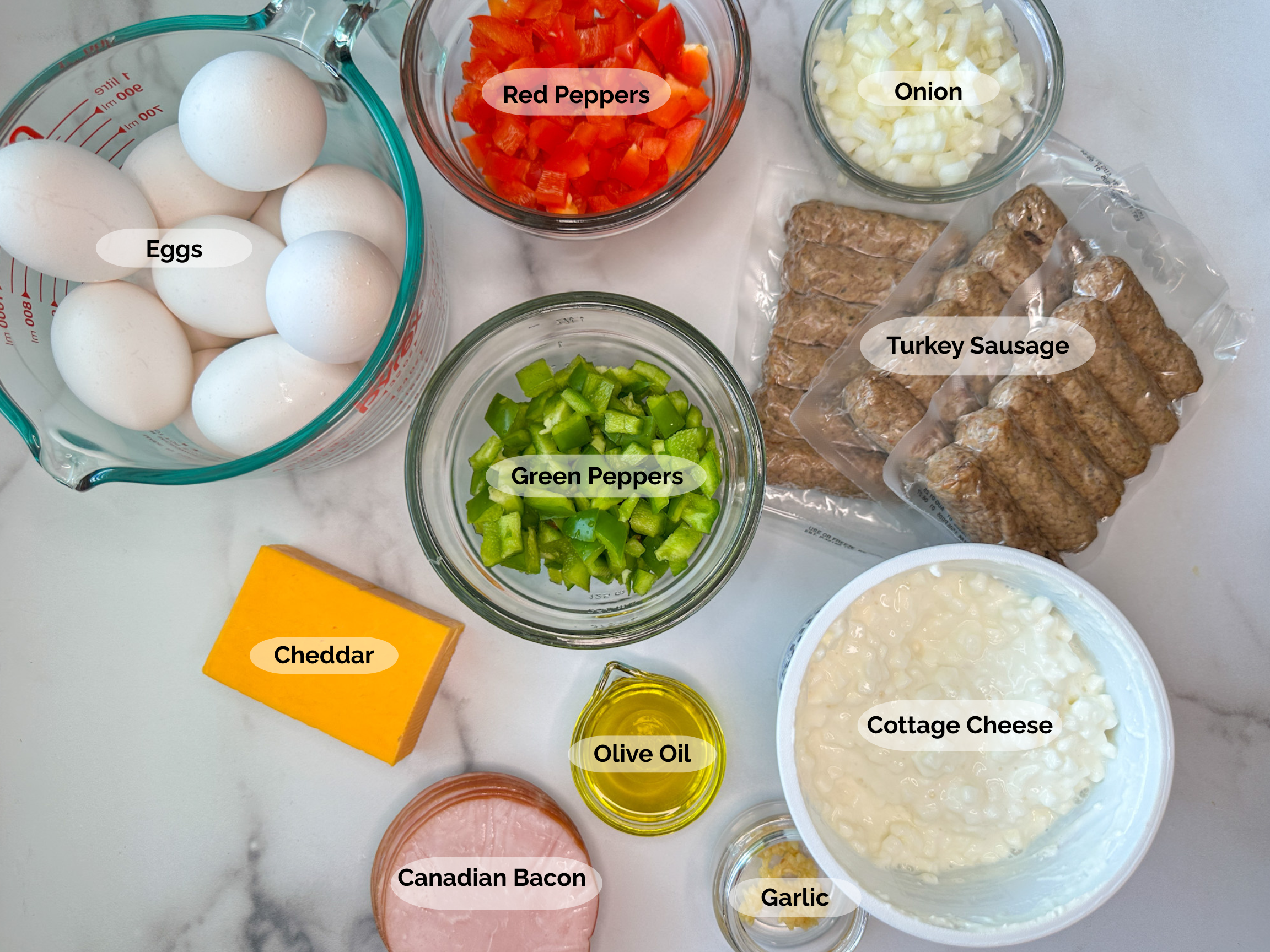 Egg and cottage cheese bake ingredients: 12 eggs, chopped red and green bell peppers, chopped onion, turkey sausage links, cottage cheese, cheddar cheese, canadian bacon, olive oil, and garlic.