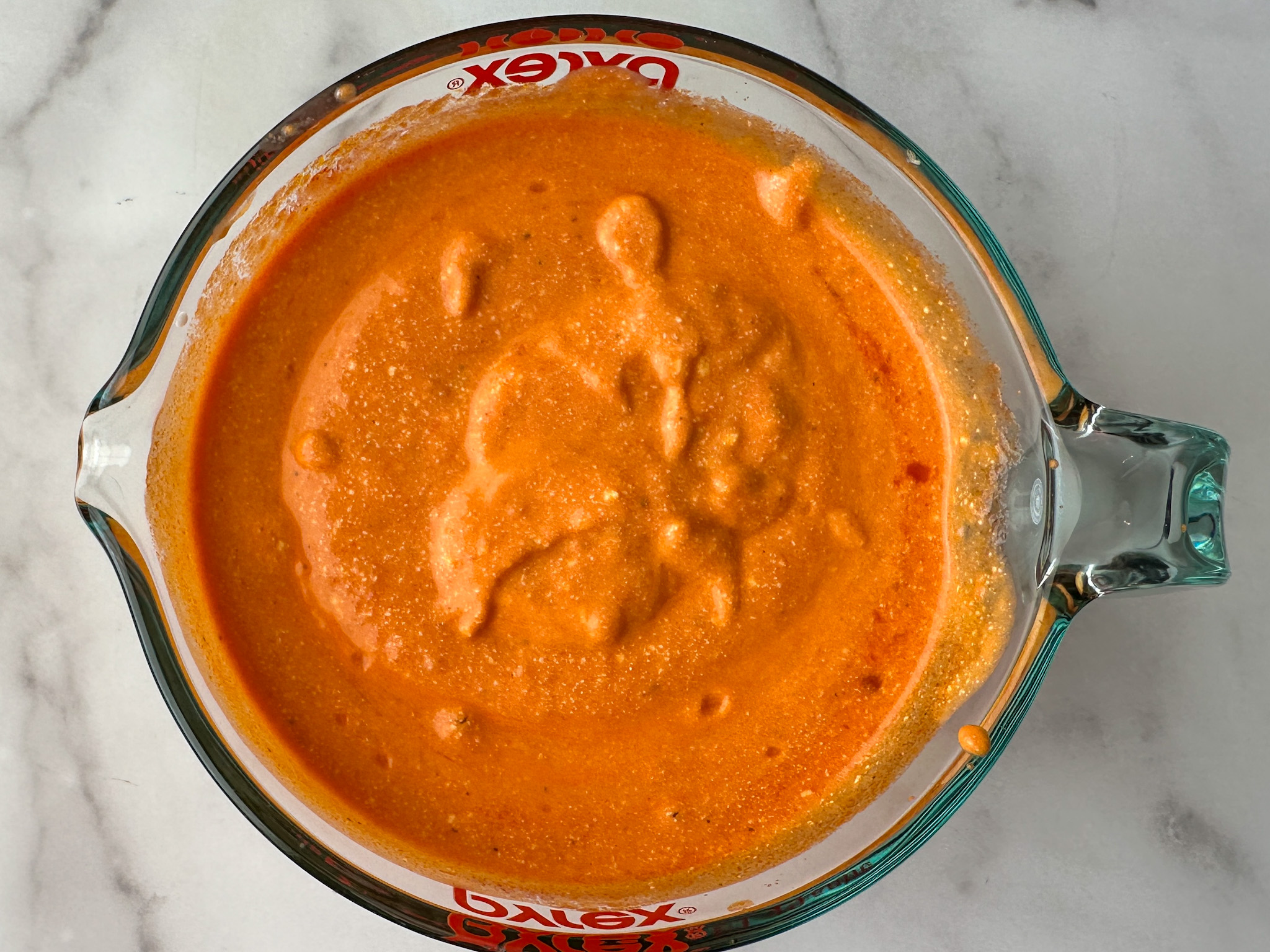 marinara sauce blended with cottage cheese for an orange sauce mixture in a large measuring cup.