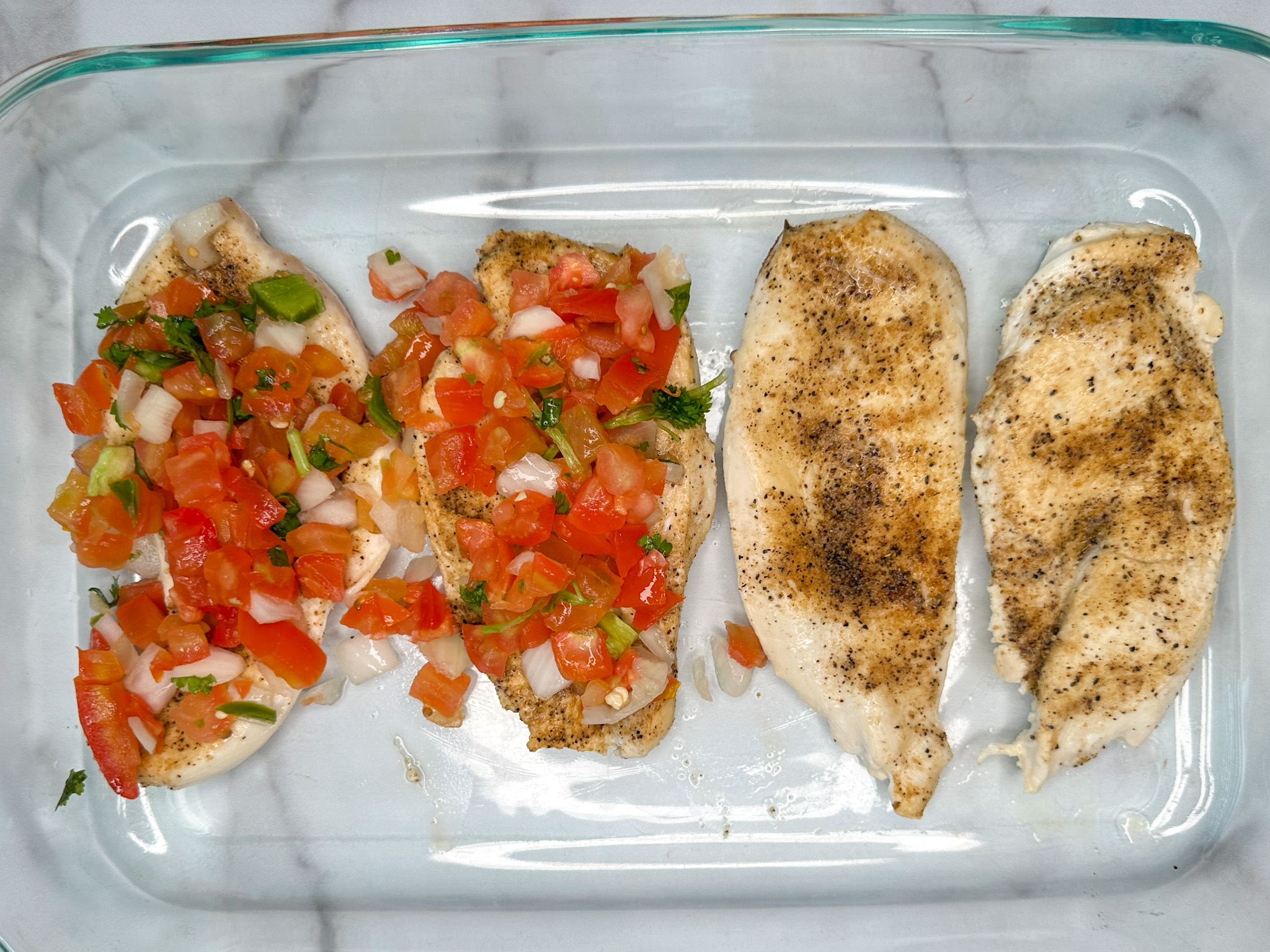 4 seared chicken breasts in a 9x13 baking dish. Two have pico de gallo on top.