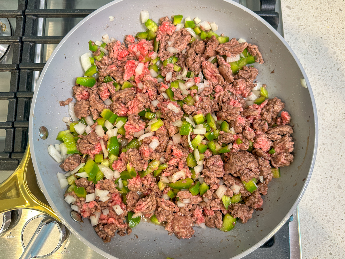 Lean ground beef, diced green peppers and onions in a large skillet.