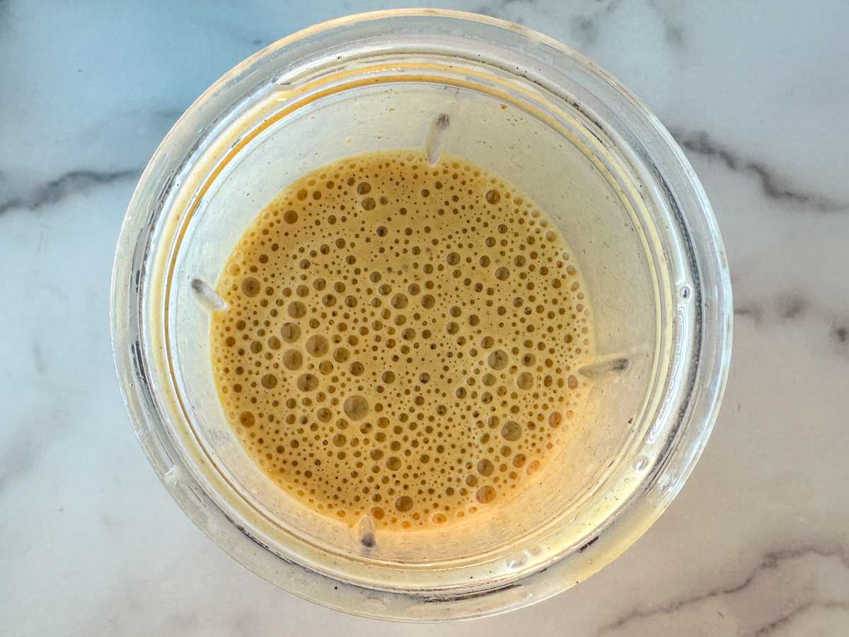 Blended pumpkin protein smoothie in a large mixing cup.