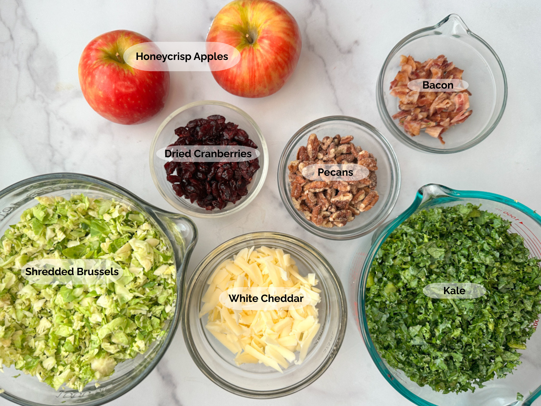 Fall brussels sprouts and apple salad ingredients: shredded brussels sprouts, 2 honeycrisp apples, dried cranberries, pecans, bacon, kale, and white cheddar