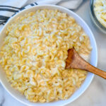 High Protein Mac and Cheese in a large bowl with a side of shredded white cheddar.