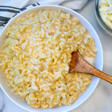 High Protein Mac and Cheese in a large bowl with a side of shredded white cheddar.