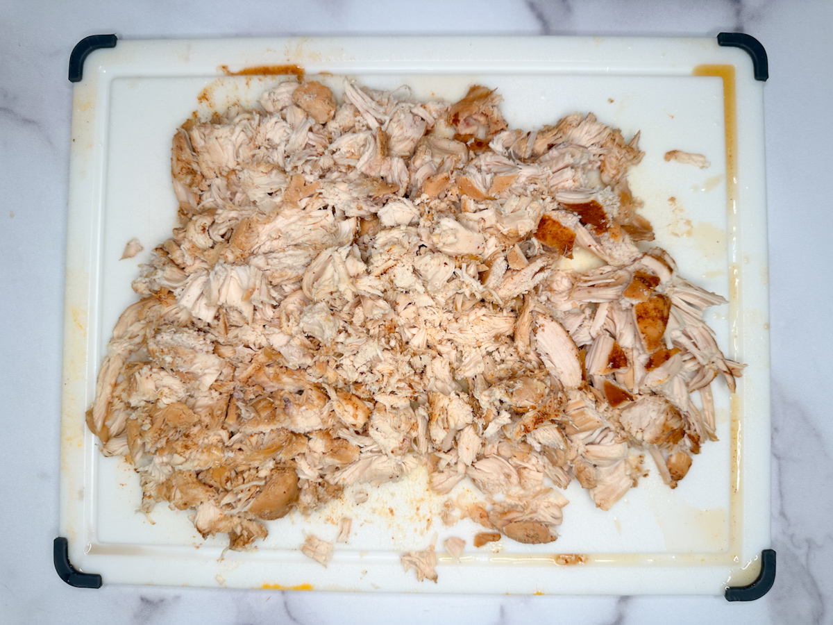 2 lbs of shredded chicken breasts on a cutting board.