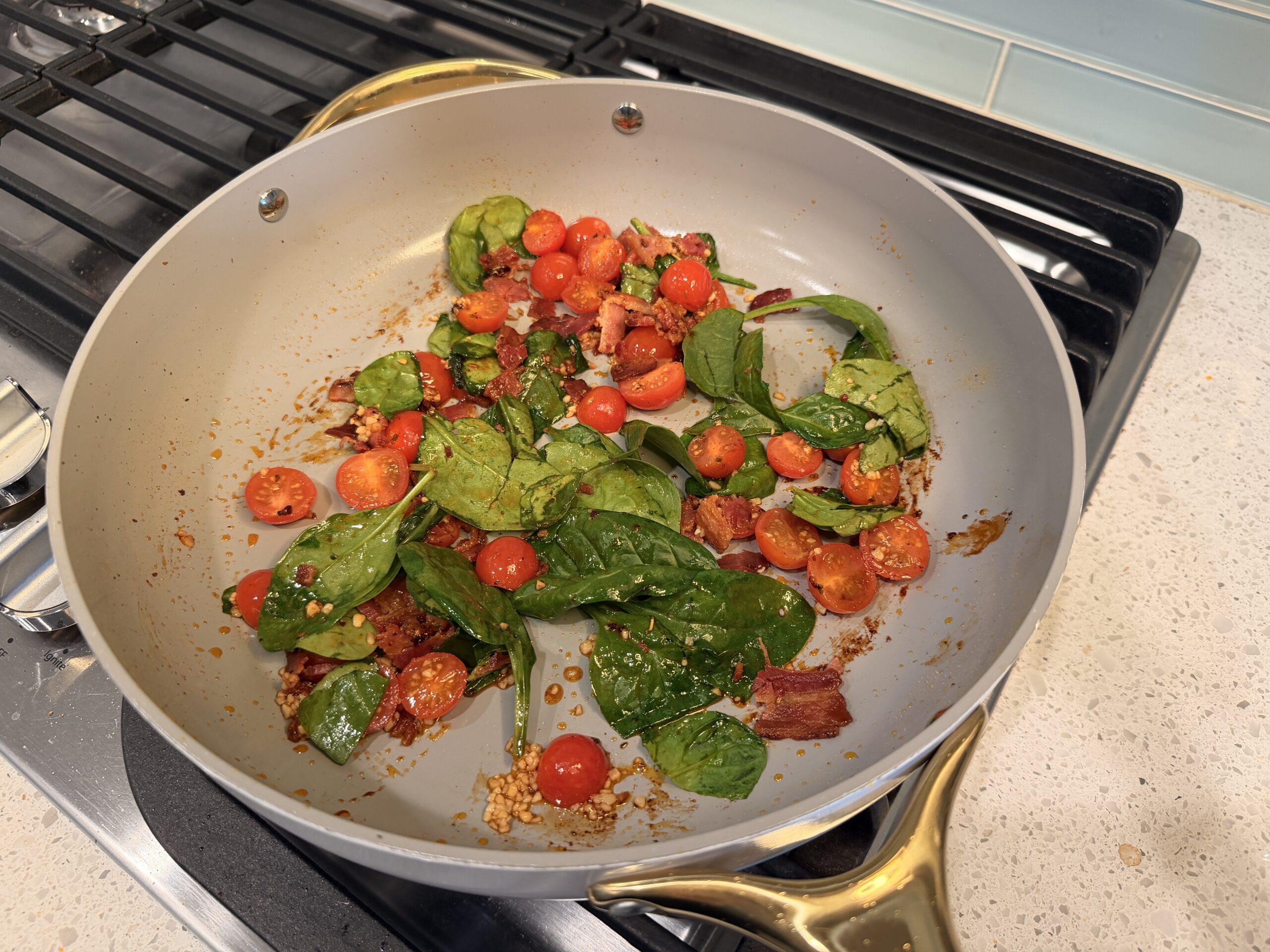 Spinach, Bacon, and Garlic sauteeing in a large skillet.