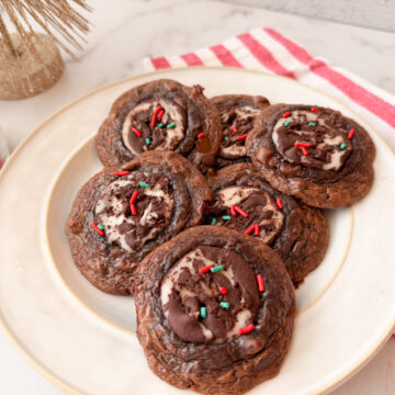 Fudgy Peppermint Brownie Cookies - 6 baked cookies on a plate topped with red and green sprinkles.