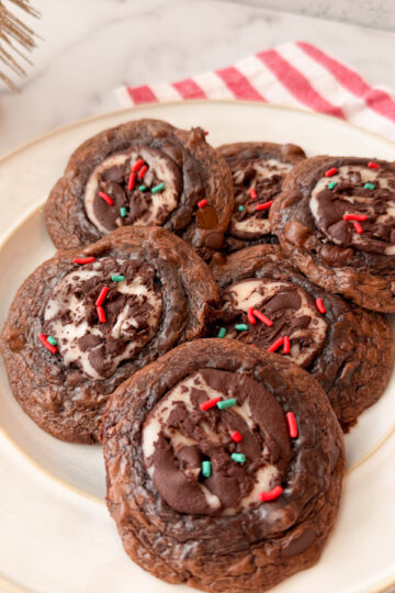 Fudgy Peppermint Brownie Cookies - 6 baked cookies on a plate topped with red and green sprinkles.