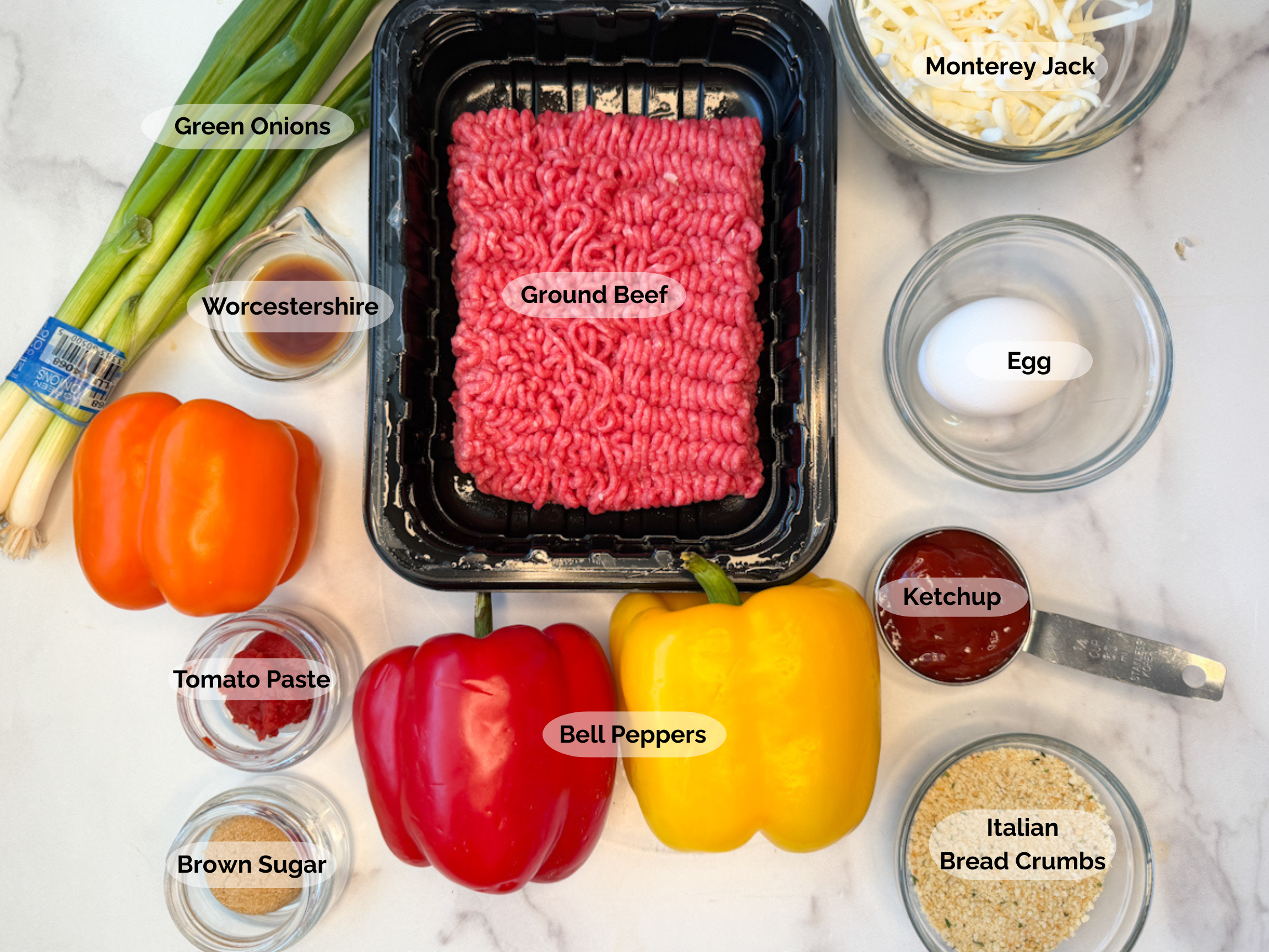 Bell pepper meatloaf ingredients: ground beef, monterey jack cheese, egg, red, yellow, and orange bell peppers, ketchup, Italian bread crumbs, brown sugar, tomato paste, Worcestershire sauce, and green onions.
