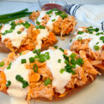 4 baked sweet potato halves topped with a shredded buffalo chicken and topped with drizzled ranch and sliced green onions.