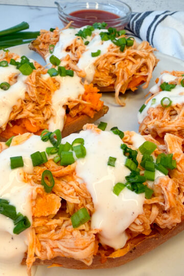 4 baked sweet potato halves topped with a shredded buffalo chicken and topped with drizzled ranch and sliced green onions.