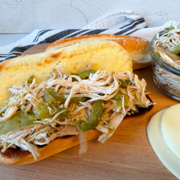 chicken philly sandwich with a hoagie bun, melted provolone cheese, and a cooked chicken, green pepper, and onion mixture filling the bun.
