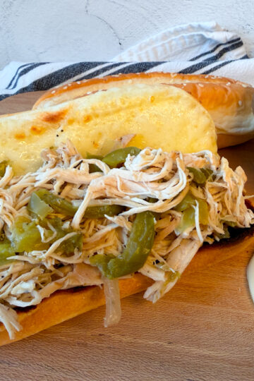 chicken philly sandwich with a hoagie bun, melted provolone cheese, and a cooked chicken, green pepper, and onion mixture filling the bun.