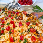 Healthy Chicken Taco Casserole in a 9x13 baking dish topped with quartered cherry tomatoes and sliced green onions.