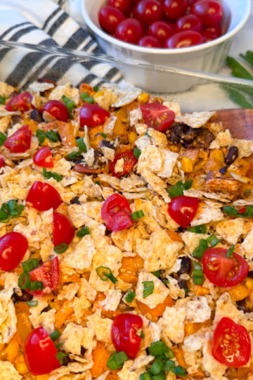 Healthy Chicken Taco Casserole in a 9x13 baking dish topped with quartered cherry tomatoes and sliced green onions.
