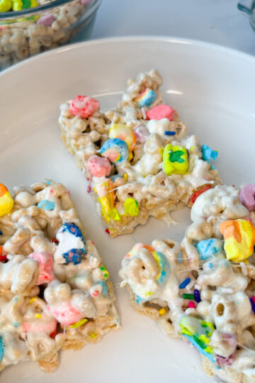 Lucky Charm Rice Krispie treats - 3 bars on a white plate with colorful marshmallows on top.
