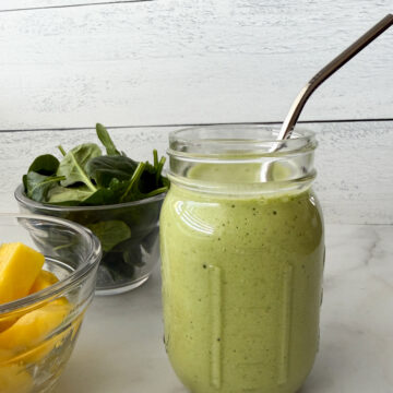 Pineapple Spinach Smoothie in a mason jar with a side of pineapple and spinach off to the side.