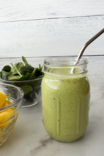 Pineapple Spinach Smoothie in a mason jar with a side of pineapple and spinach off to the side.