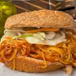 shredded bbq chicken topped with cole slaw and a whole wheat bun