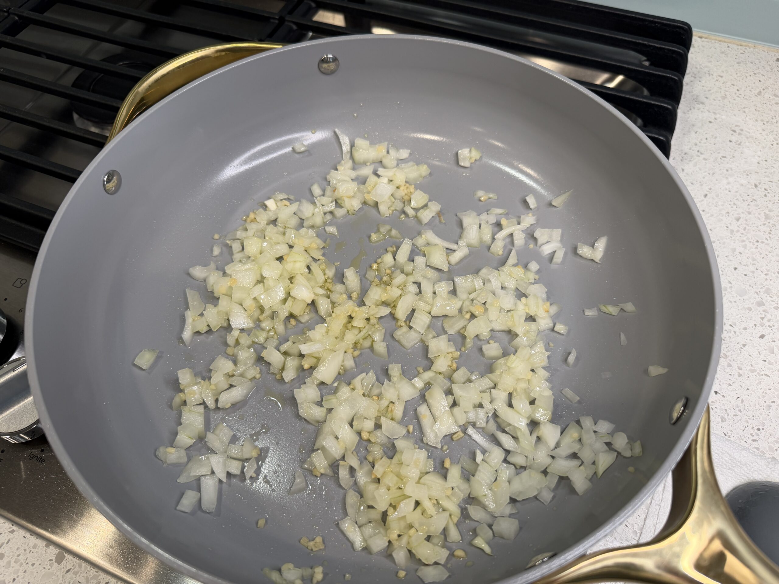 Chopped onions being sauteed in a large skillet.