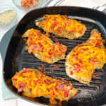 4 grilled bacon ranch chicken breasts in a grill skillet topped with crumbled bacon and melted cheddar cheese.