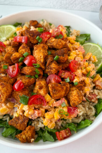 Street Corn Chicken Rice Bowl with lettuce, rice, grilled chicken, chopped tomatoes, corn, and peppers.