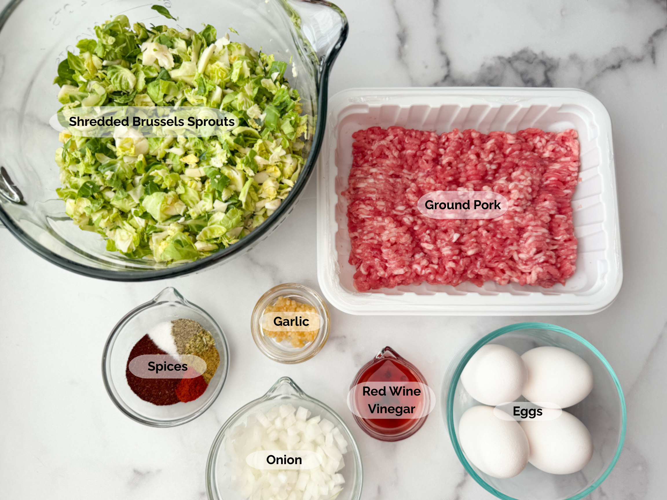 Spicy Pork Brussels Bowl ingredients: shredded brussels sprouts, ground pork, chopped onion, red wine vinegar, spices, garlic, and 4 eggs.
