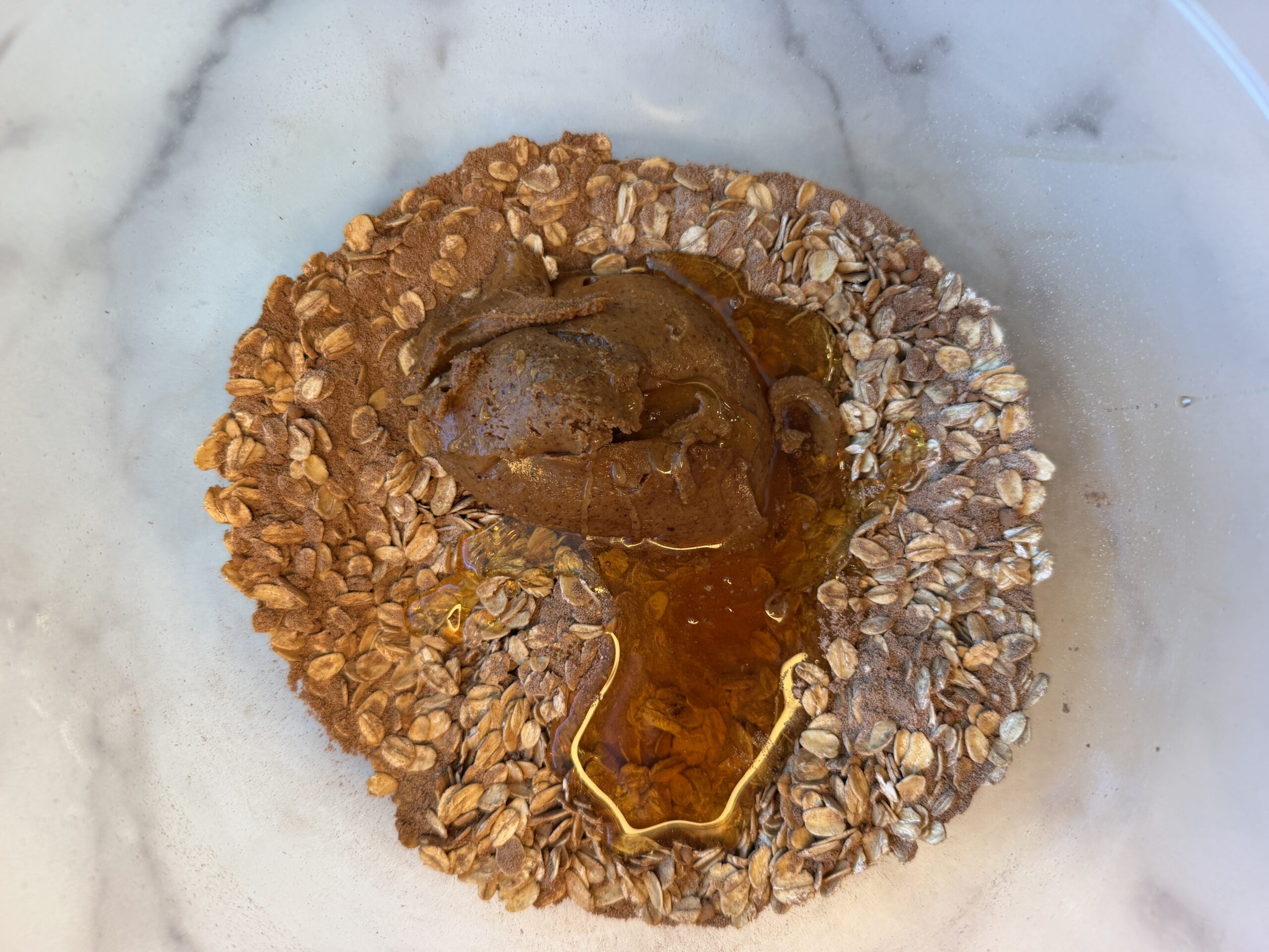 Oats, protein powder, salt, cocoa powder mixed together in a bowl and topped with almond butter and honey.