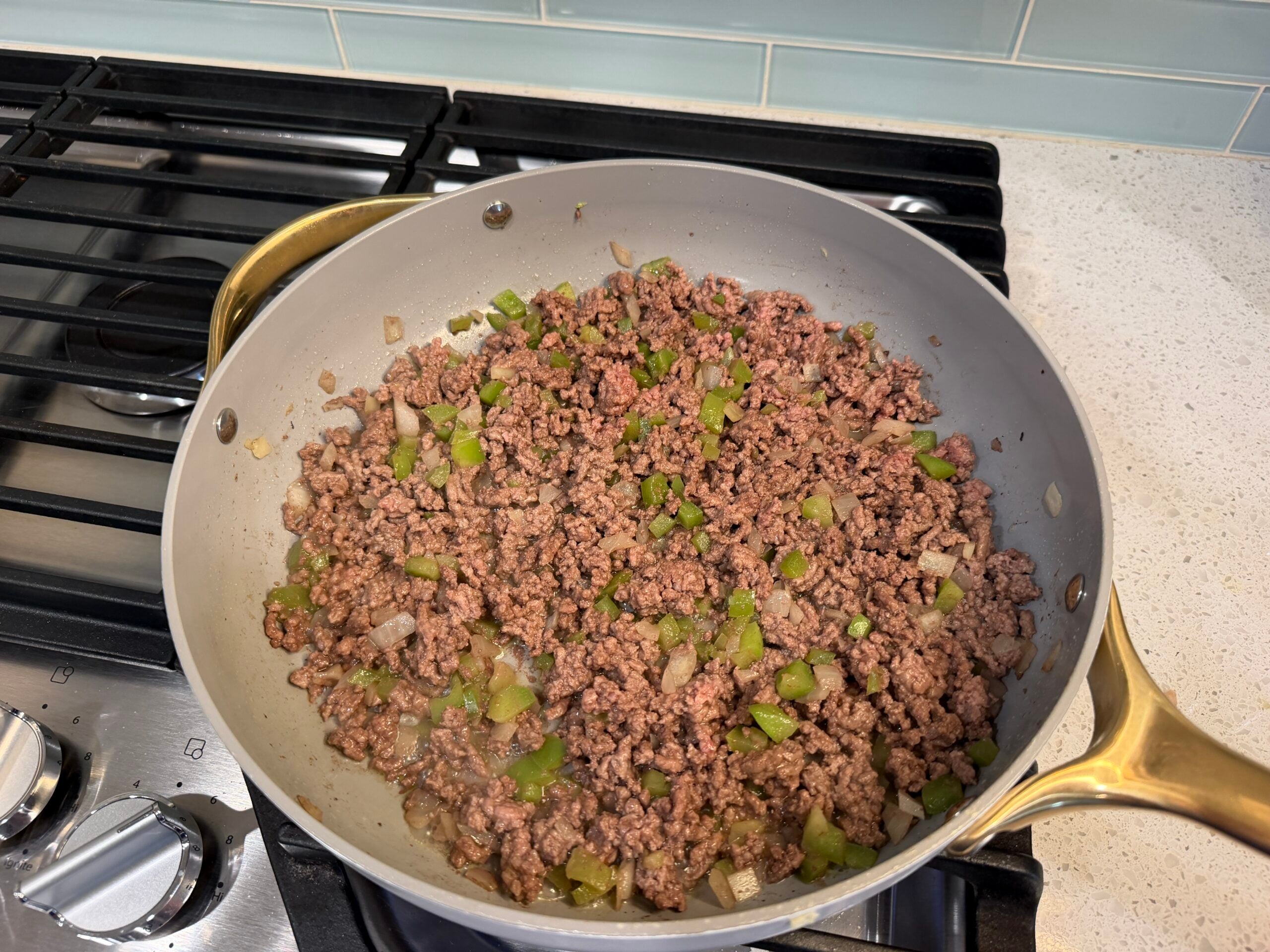 Ground beef browning with onion and green pepper in a skillet
